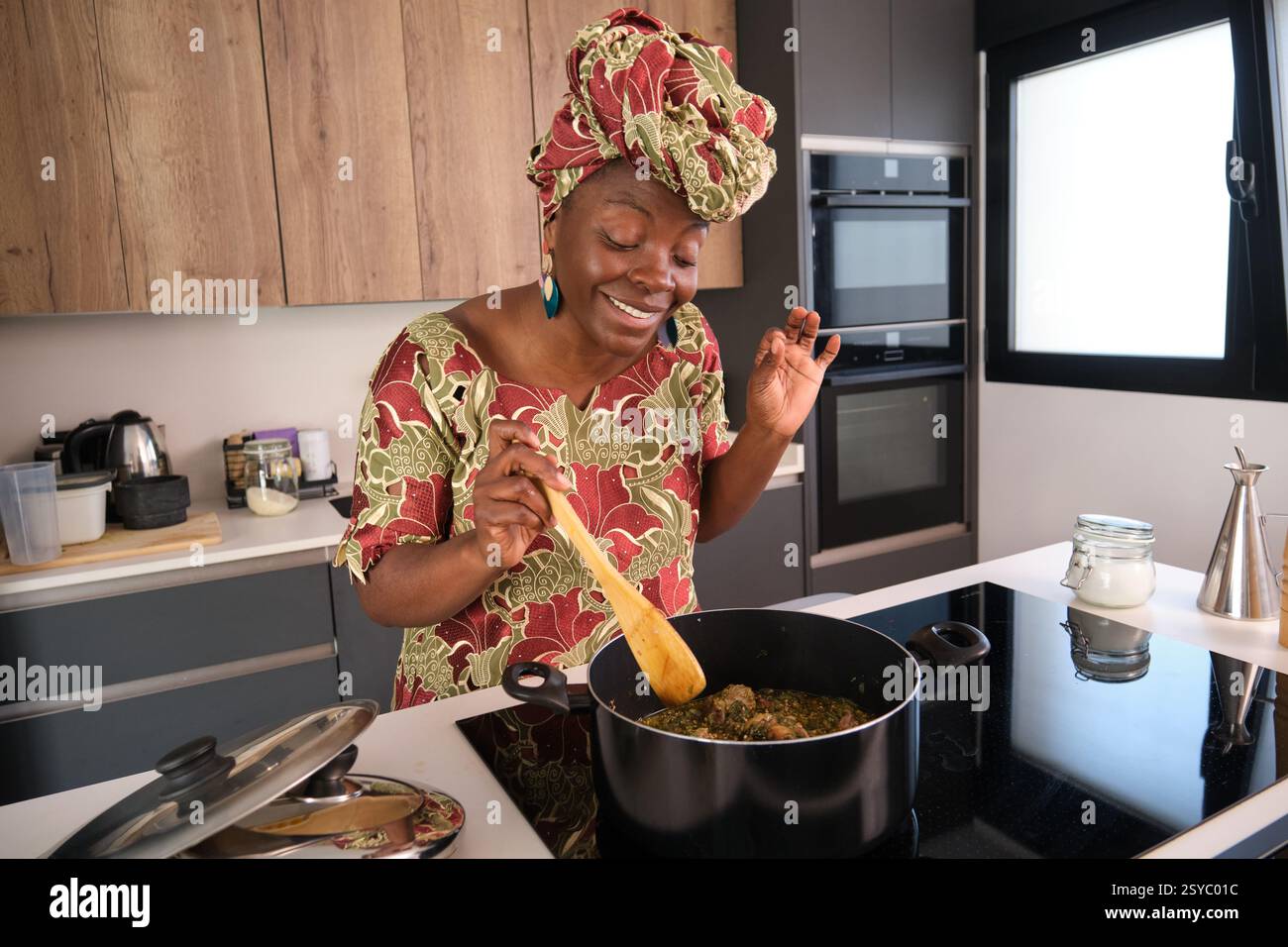 Femme africaine cuisinant la soupe traditionnelle d'okra avec des épinards dans la cuisine Banque D'Images