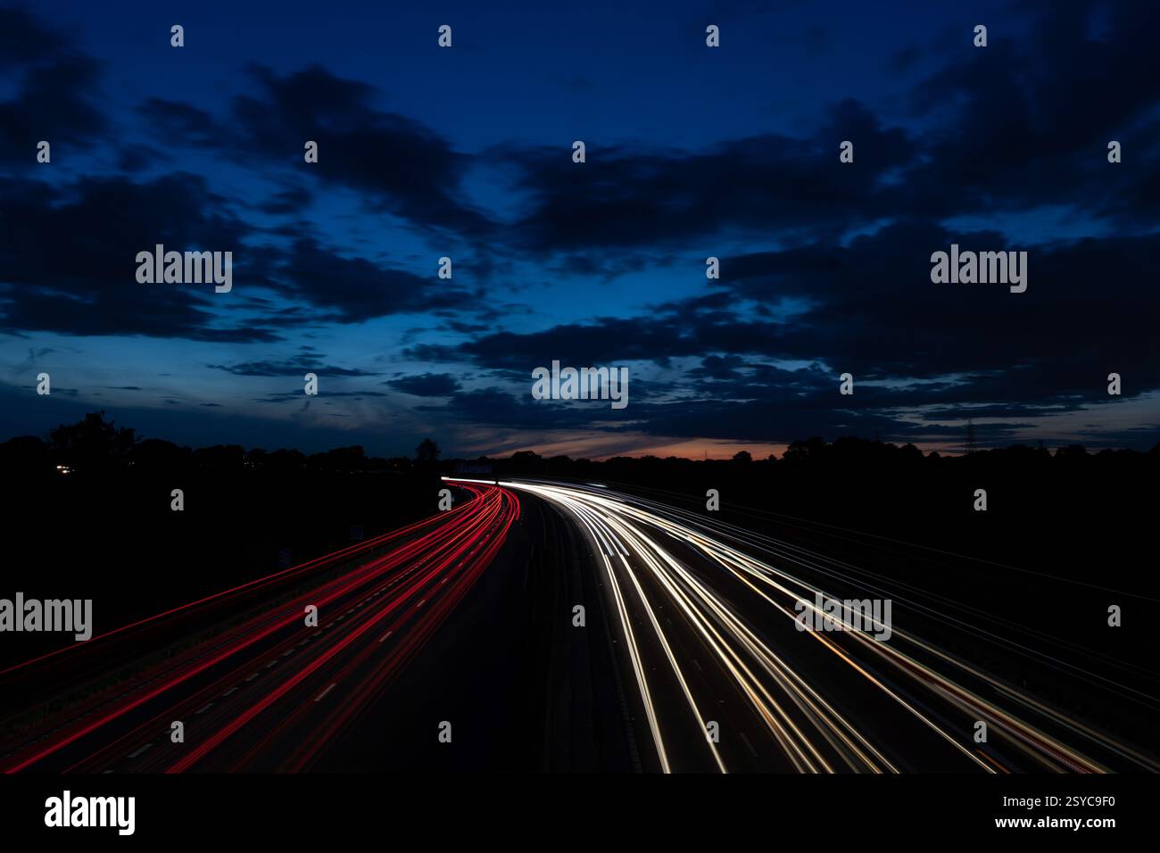 Autoroute de nuit longue exposition avec lumières floues et ciel nuageux spectaculaire Banque D'Images
