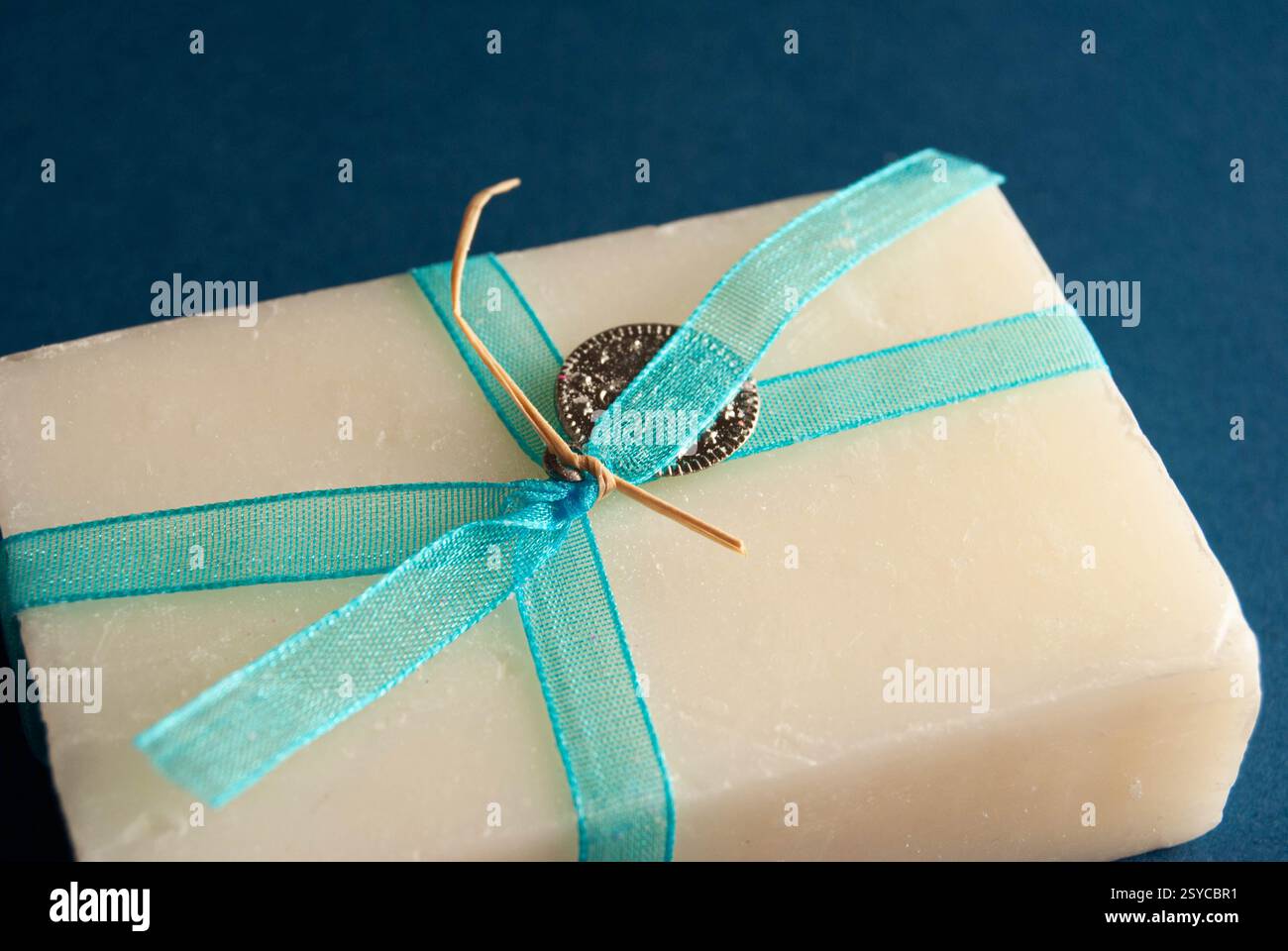 Pains de savon à la main bleus et blancs ornés de noeuds décoratifs sur un fond bleu doux. Banque D'Images