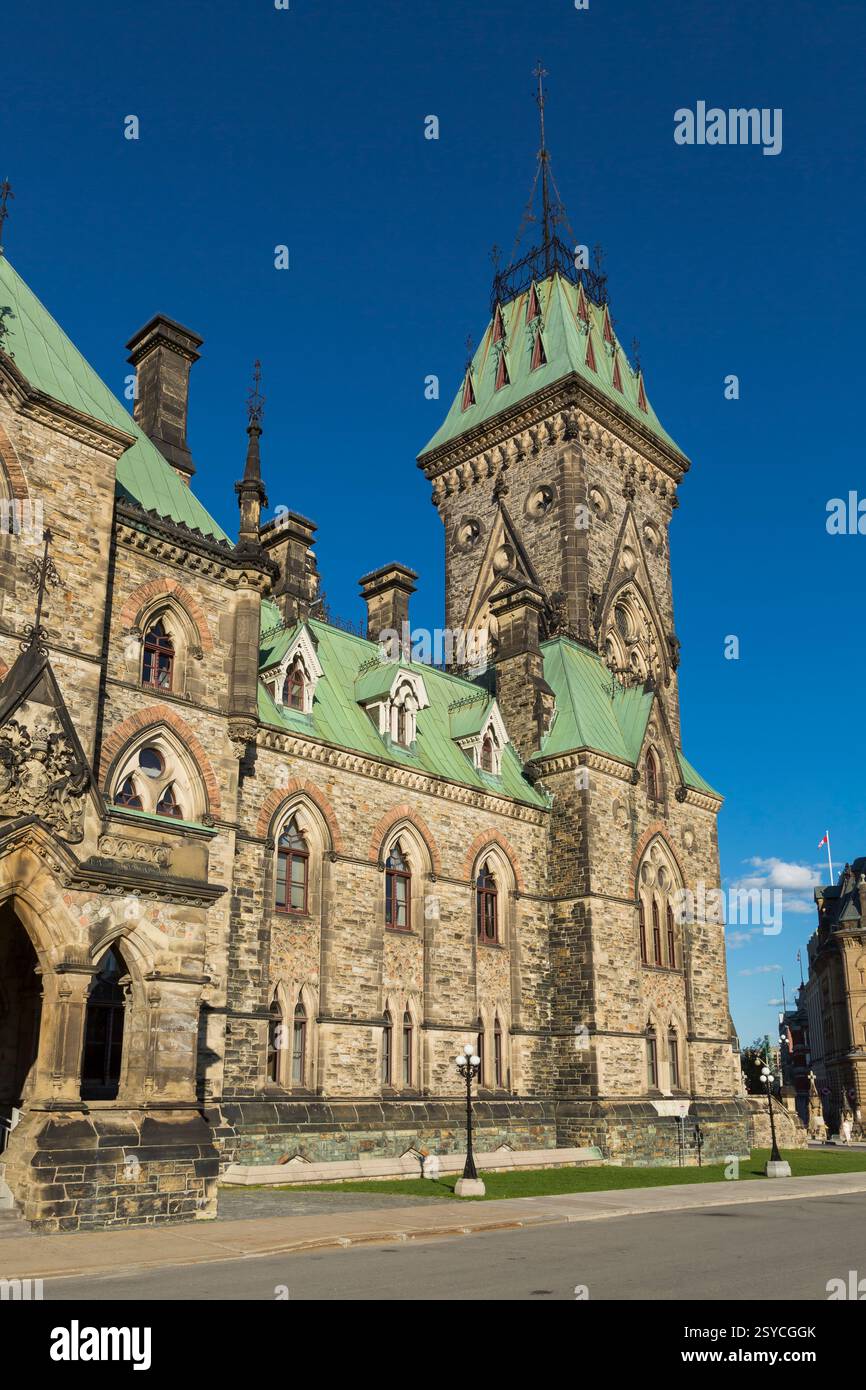Grand bâtiment avec un toit vert et une tour de l'horloge. Le bâtiment est entouré d'un trottoir Banque D'Images