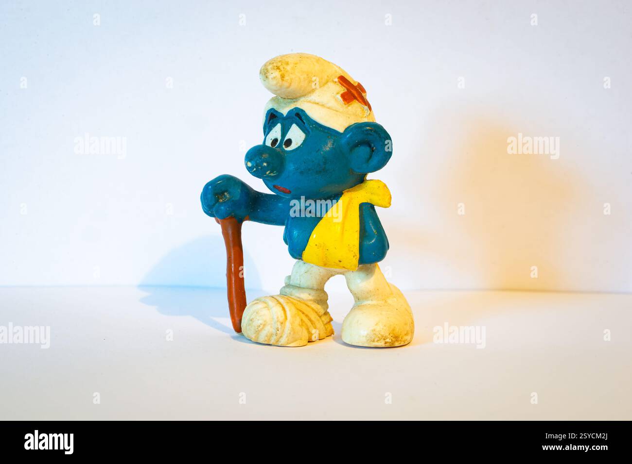 Figure bleue et blanche connue sous le nom de smurf. Dans ce cas, il s'agit d'un smurf qui a un bras et un pied cassés. Jouet sur fond blanc. Banque D'Images