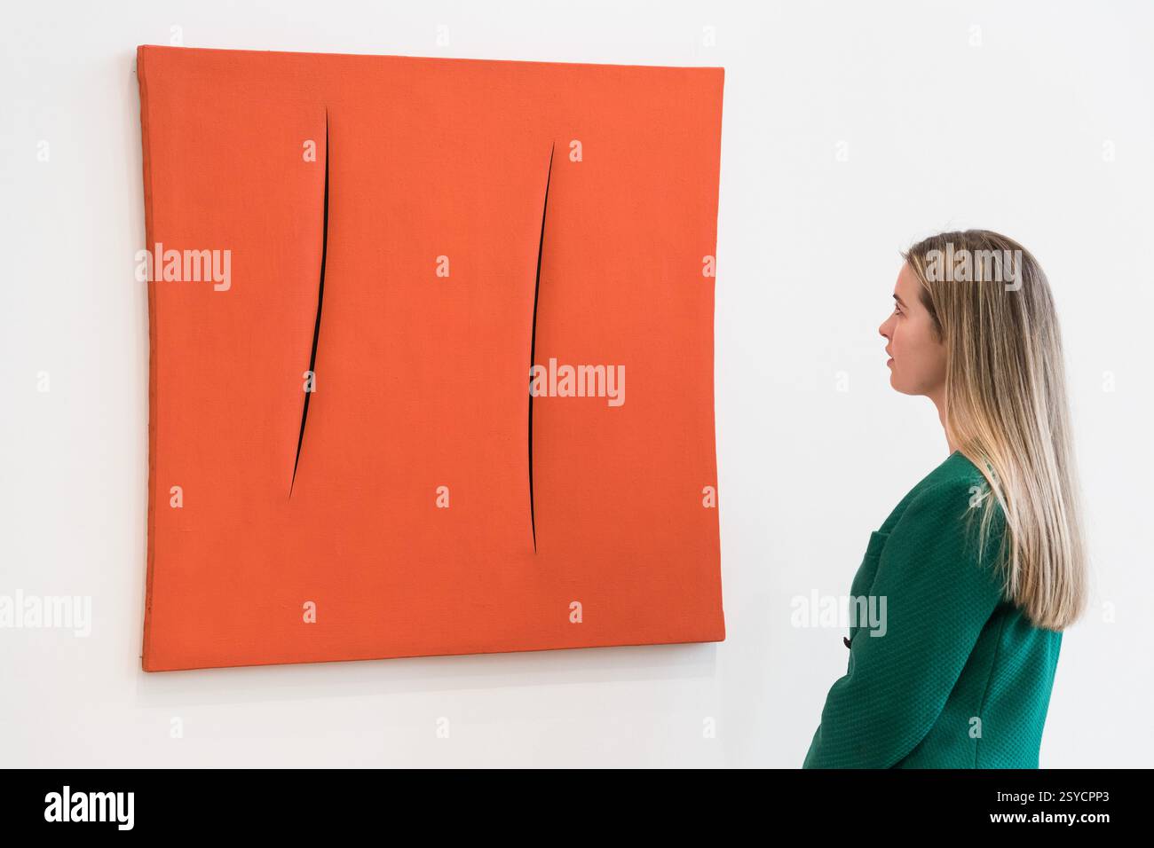 Londres, Royaume-Uni. 28 février 2025. LONDRES, ROYAUME-UNI - 28 FÉVRIER 2025 : un membre du personnel regarde un tableau de Lucio Fontana, “Concetto spaziale, Attese”, estimation : £1 000 000 - 2 000 000 lors d'une visite photo à la maison de vente aux enchères Phillips présentant les points forts des ventes aux enchères d'art moderne et contemporain à Londres, Royaume-Uni, le 28 février 2025. (Photo de Wiktor Szymanowicz/NurPhoto) crédit : NurPhoto SRL/Alamy Live News Banque D'Images