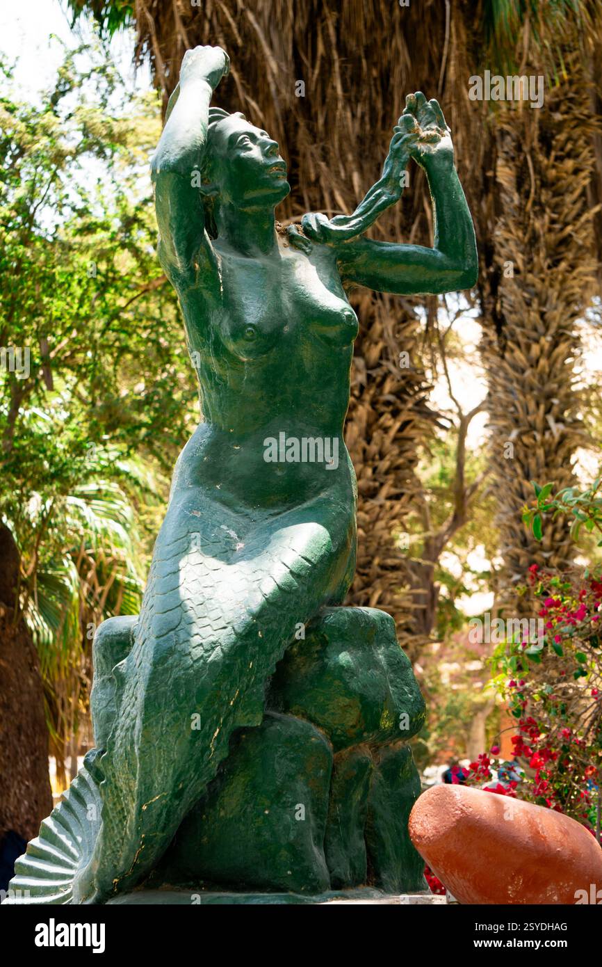 Une belle statue à l'oasis de Huacachina à ICA Pérou entourée de palmiers et de dunes de sable dorées du désert Banque D'Images