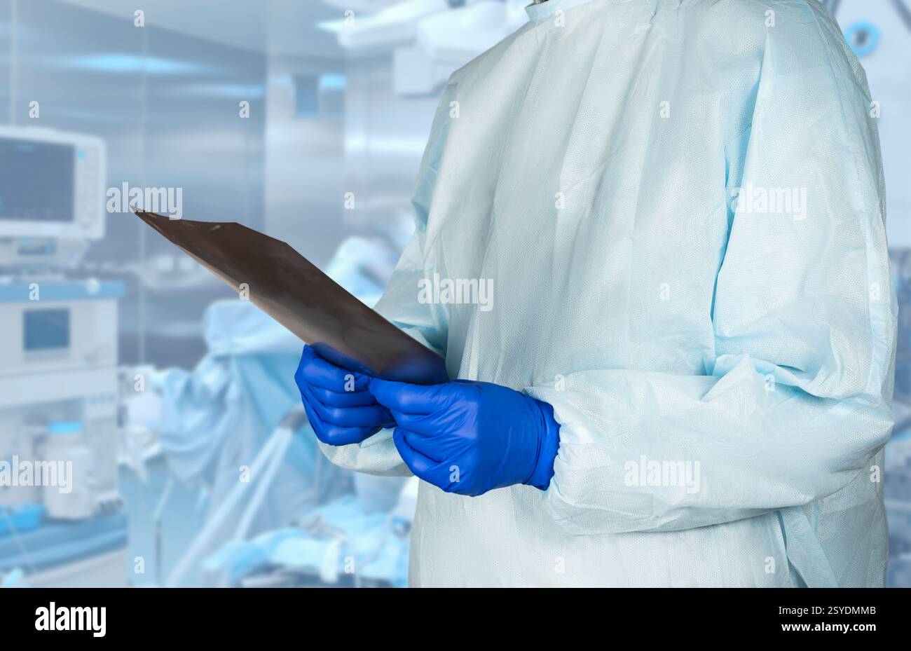 Un professionnel de la santé portant des vêtements de protection observe les rayons X dans un cadre chirurgical stérile, assurant ainsi les soins et la sécurité du patient. Banque D'Images