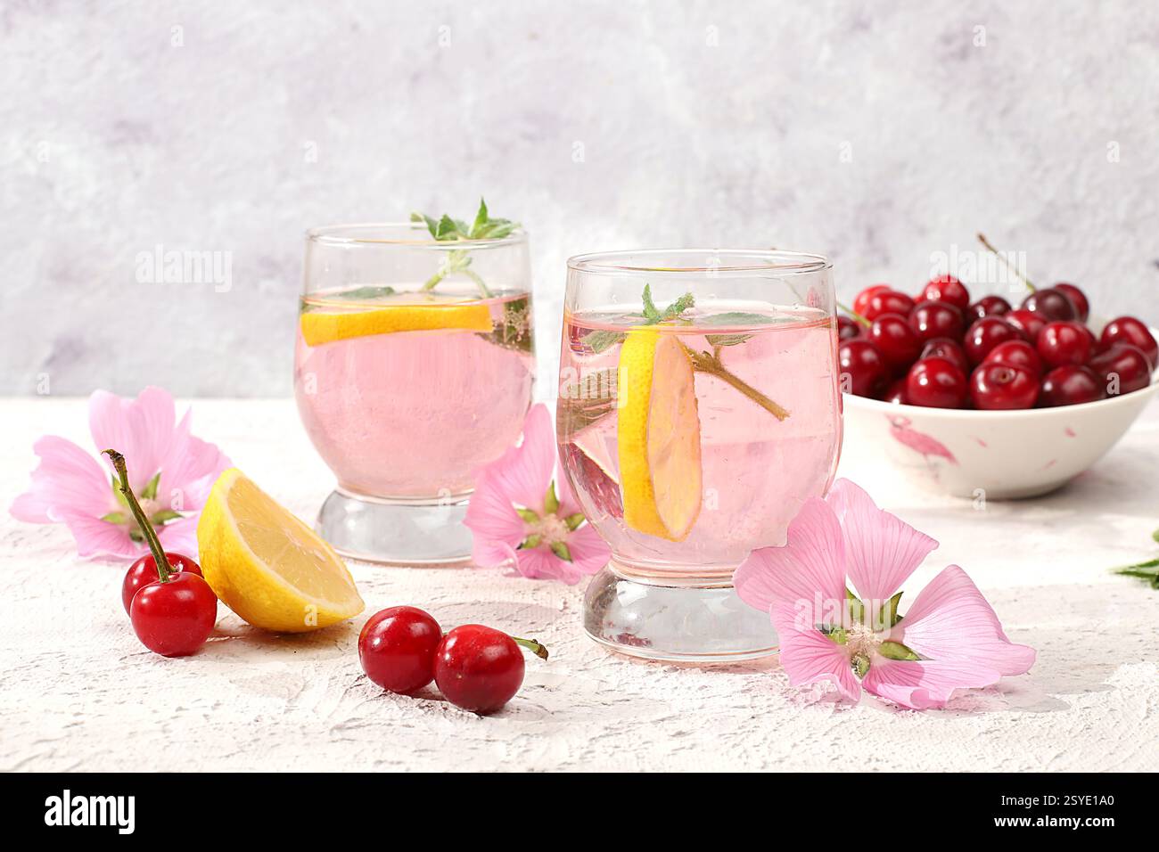 Thé glacé cerise ou cocktail de menthe et citron, une recette rafraîchissante de boisson estivale. Verre avec limonade aux fruits de pomme sur table en béton léger, régime de désintoxication et Banque D'Images