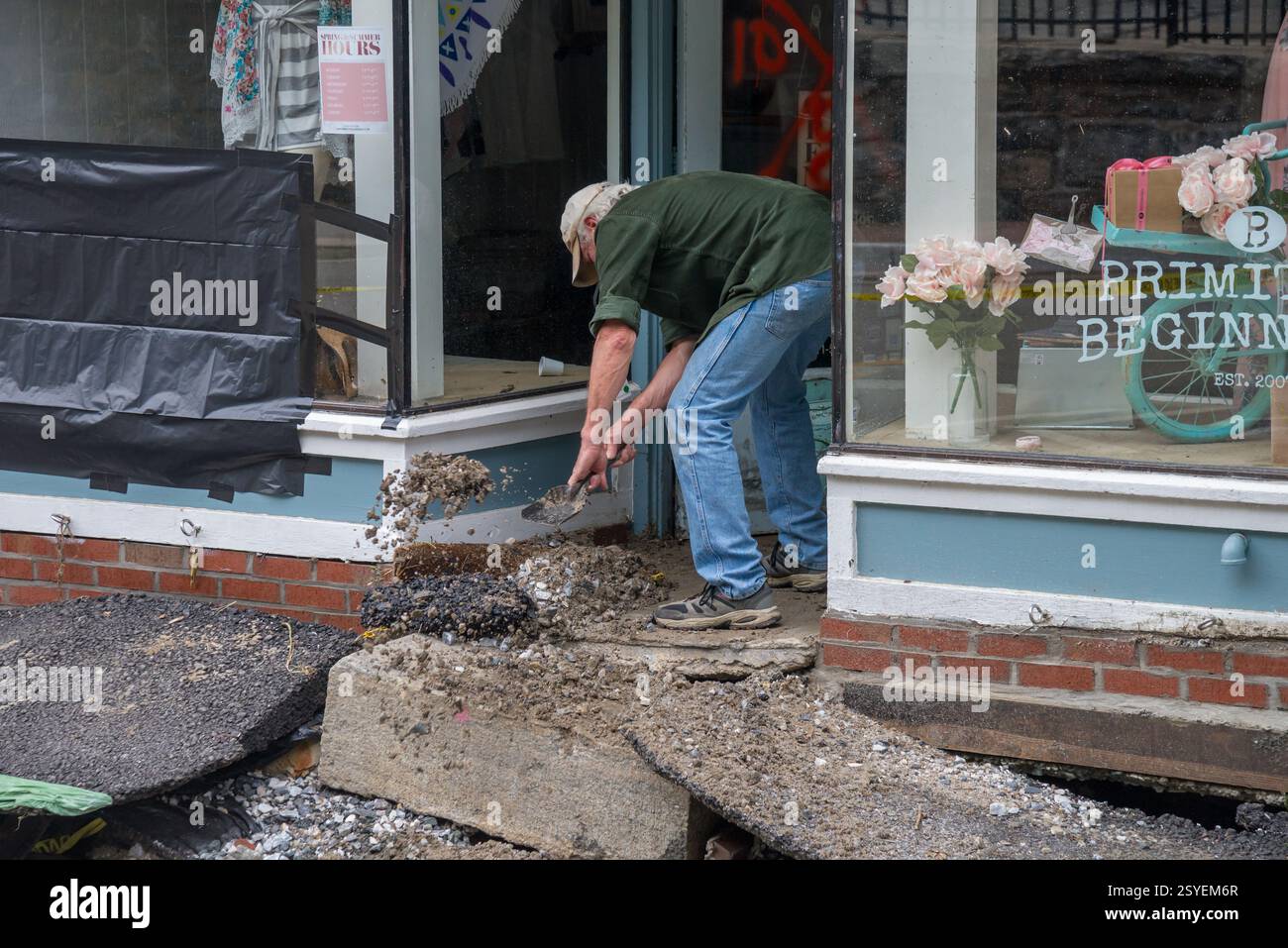 Le propriétaire de primitive Beginnings sur la rue main à Ellicott City pelle des morceaux d'asphalte et de terre de sa porte d'entrée. Banque D'Images