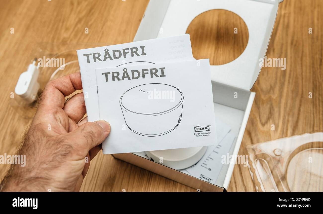 Paris, France - 17 juin 2021 : une personne tient les manuels d'instructions IKEA TRADFRI tout en déballant un hub de maison intelligente, avec l'emballage, l'adaptateur et l'appareil Banque D'Images