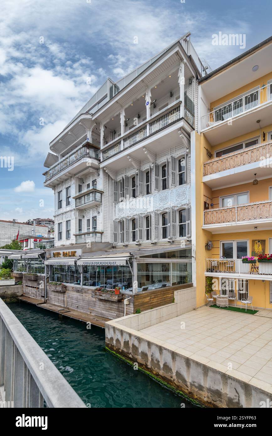 Istanbul, Turquie - 12 mai 2023 : bâtiments résidentiels traditionnels en bois près d'un étroit canal d'eau près du détroit du Bosphore à Arnavutkoy, dans le district de Besiktas, par une journée de printemps ensoleillée Banque D'Images