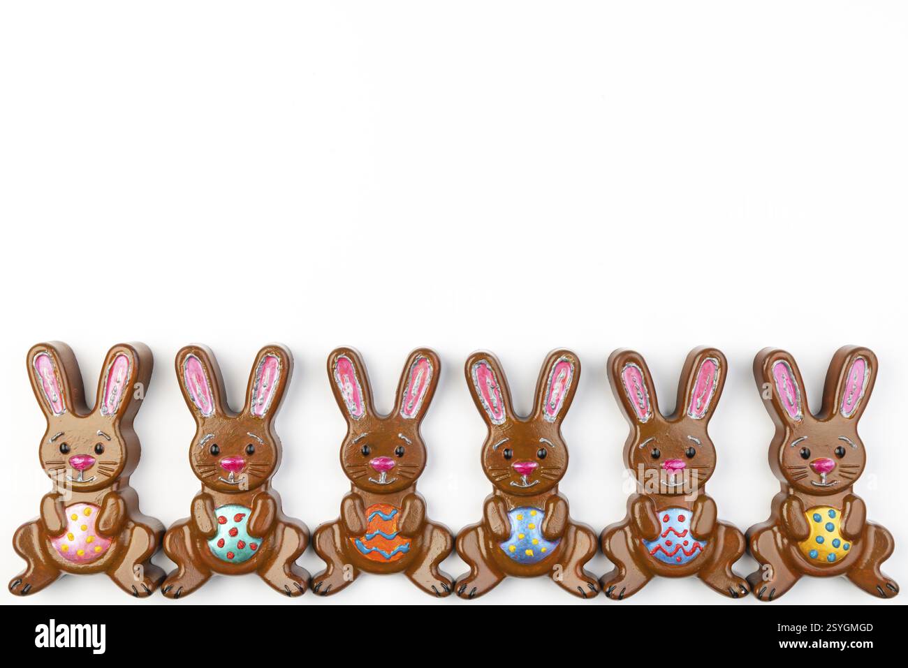Six lapins de Pâques avec des œufs colorés disposés uniformément les uns à côté des autres sur un fond blanc Banque D'Images