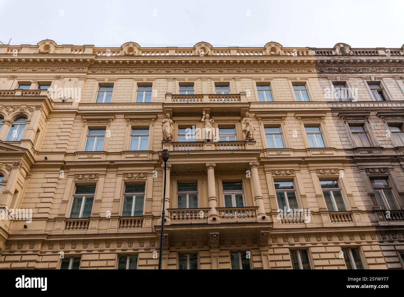 Un bâtiment historique de plusieurs étages avec une façade ornée, avec des moulures décoratives, des rangées de fenêtres et un balcon central avec des statues, se dresse agai Banque D'Images