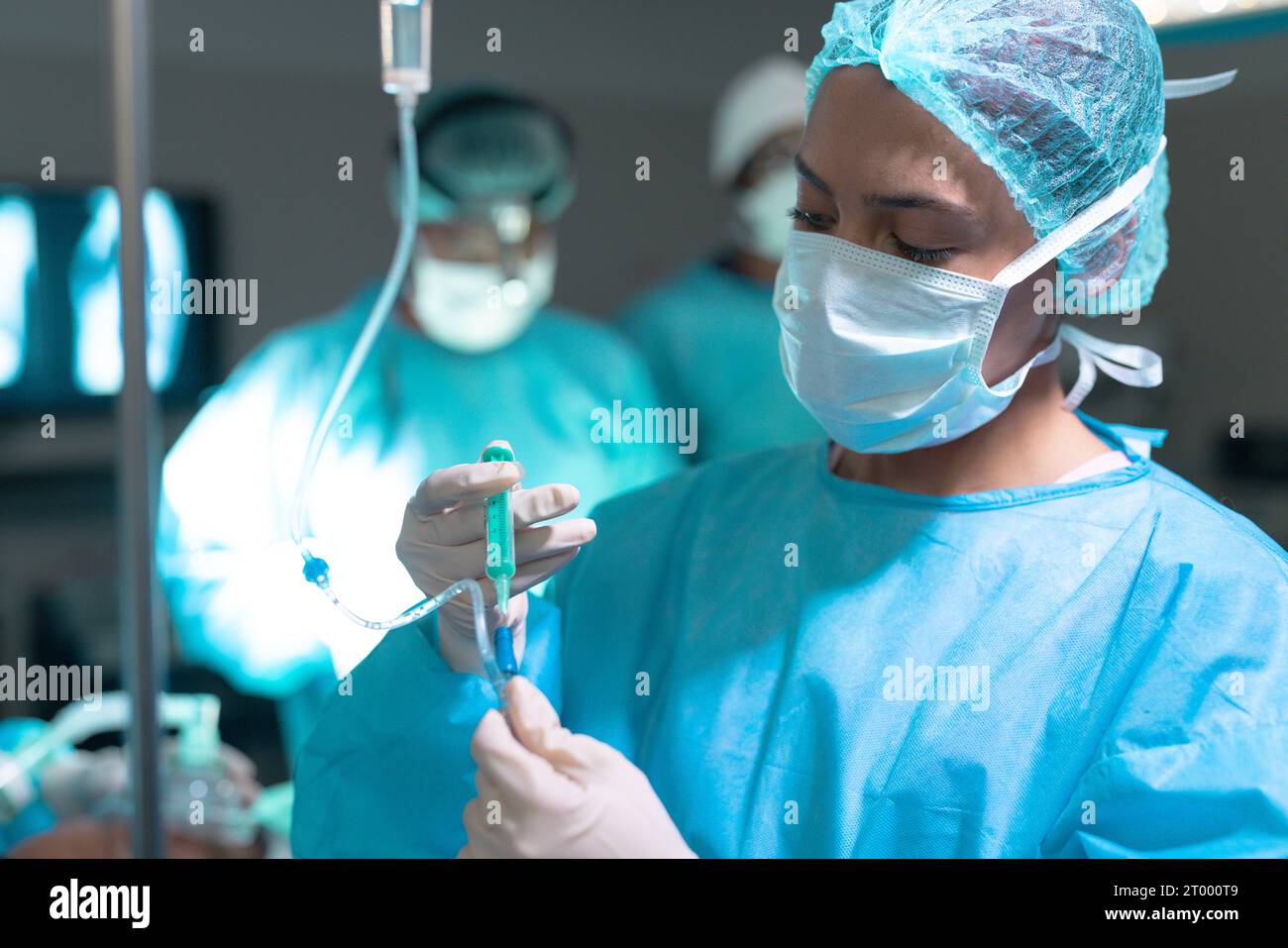 Chirurgien biracial portant une blouse de chirurgie appliquant le goutte-à-goutte en salle d'opération à l'hôpital Banque D'Images