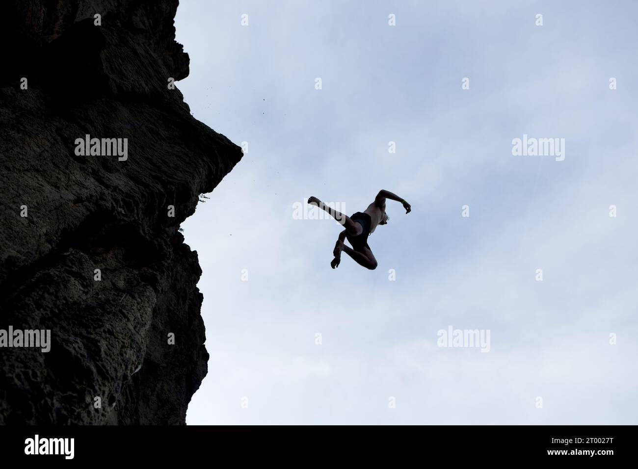 Silhouette d'homme sautant de falaise. Banque D'Images