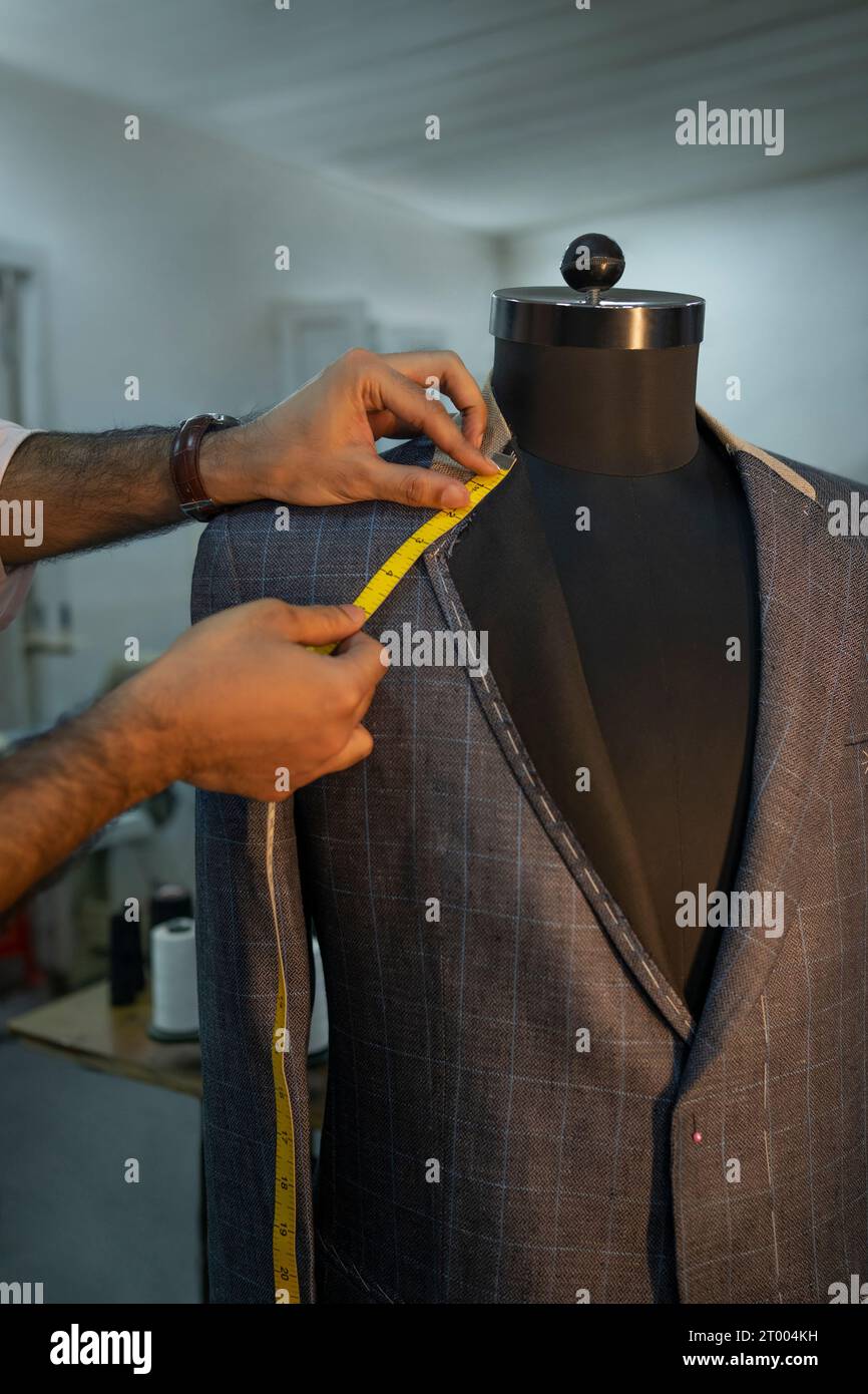 Un tailleur sur mesure vérifiant les mesures sur une forme de robe Banque D'Images