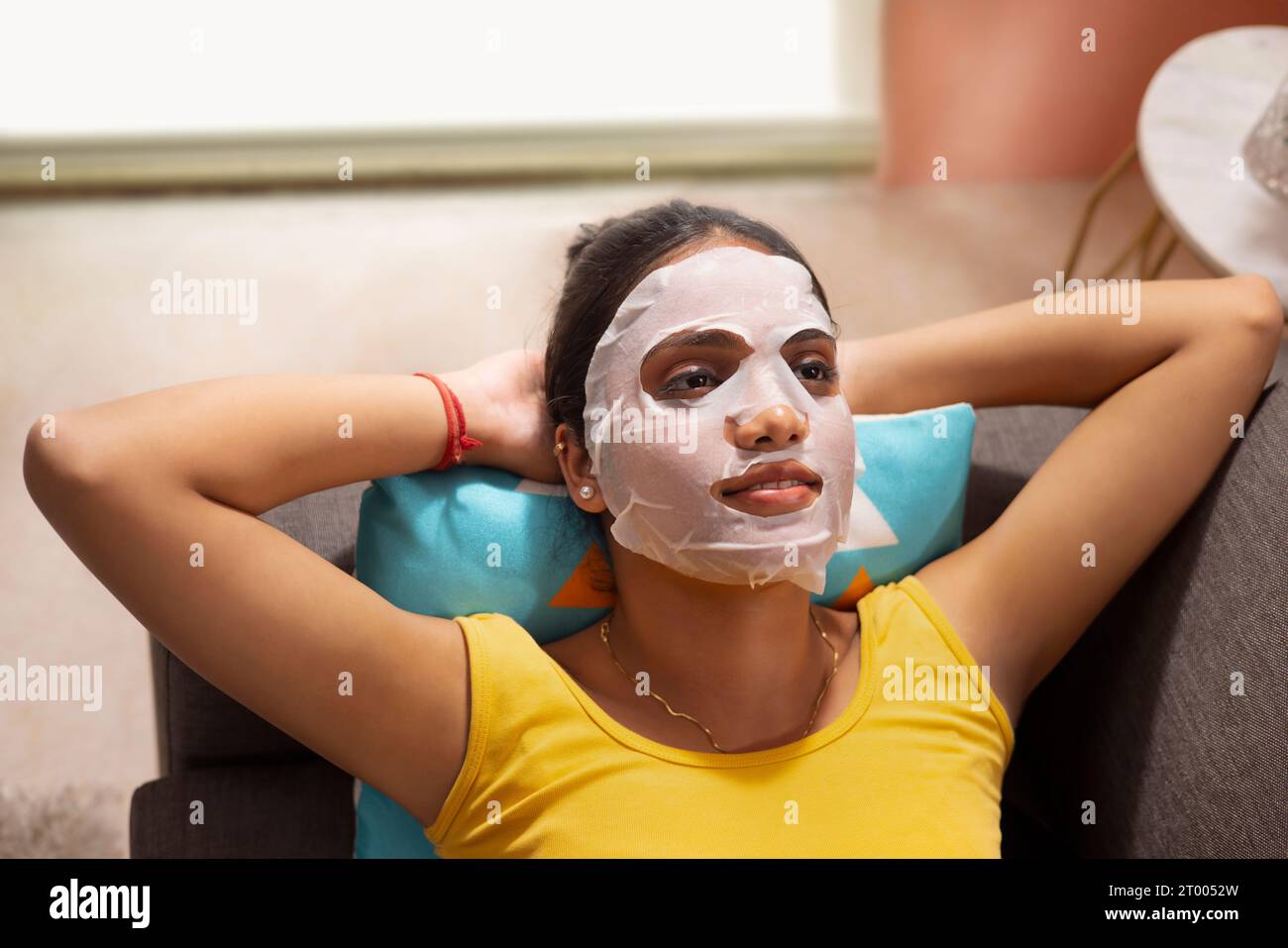 Vue d'angle de dessus de la jeune femme avec masque facial relaxant sur le canapé Banque D'Images