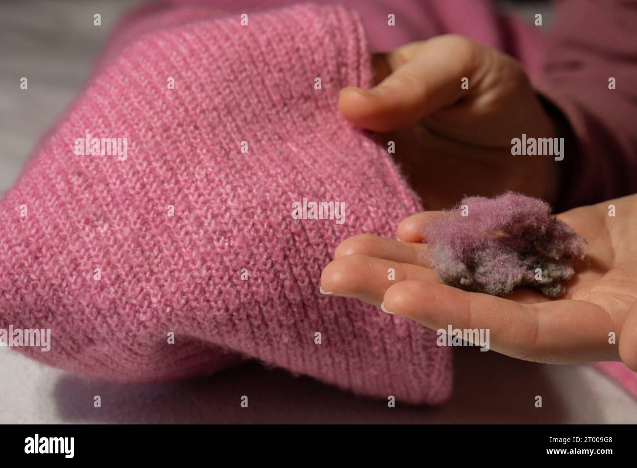 Femme utilisant le rasoir anti-boulochage à la maison. Dispositif pour raser des vêtements. Rasoir à tissu anti-peluche. Chandail portable électrique à pilule def Banque D'Images