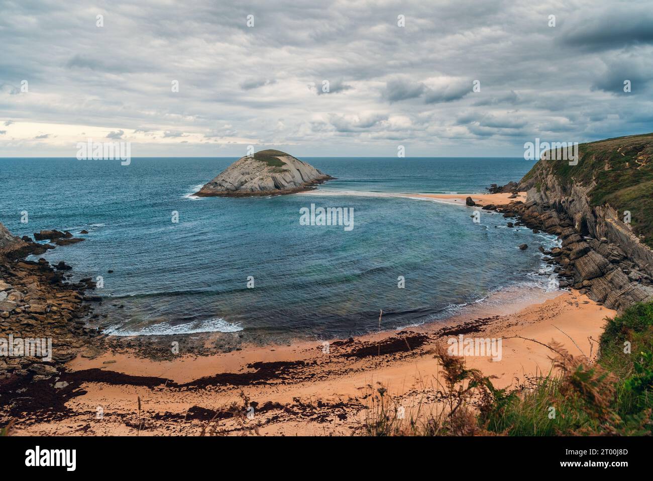 Playa de Covachos plage à Santander, Cantabrie, nord de l'Espagne avec île rocheuse et broche de sable en journée nuageuse. Destination de voyage populaire Banque D'Images