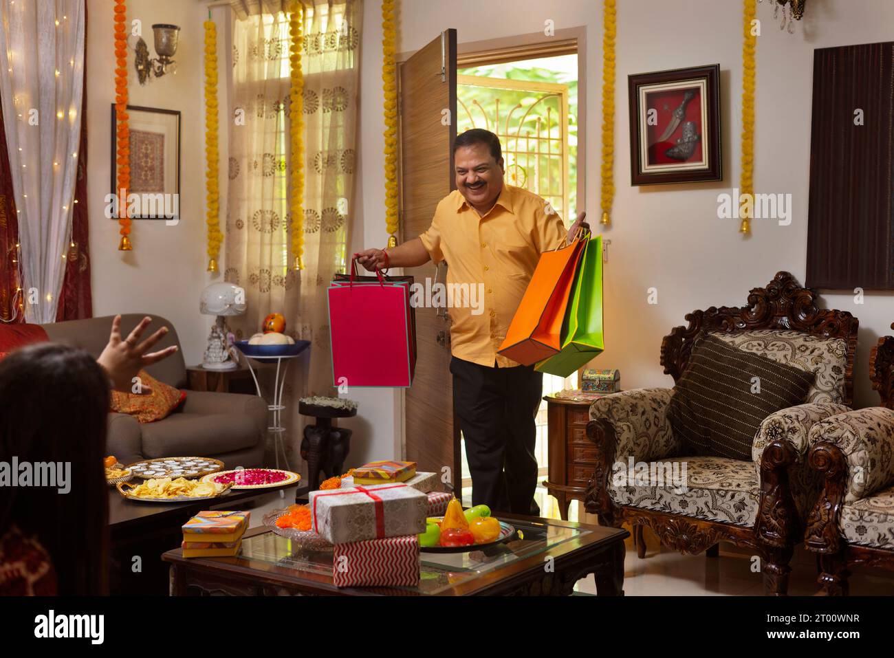 L'homme entre heureux dans la maison avec des cadeaux et des sacs à provisions pour sa famille, pendant le festival de Diwali Banque D'Images