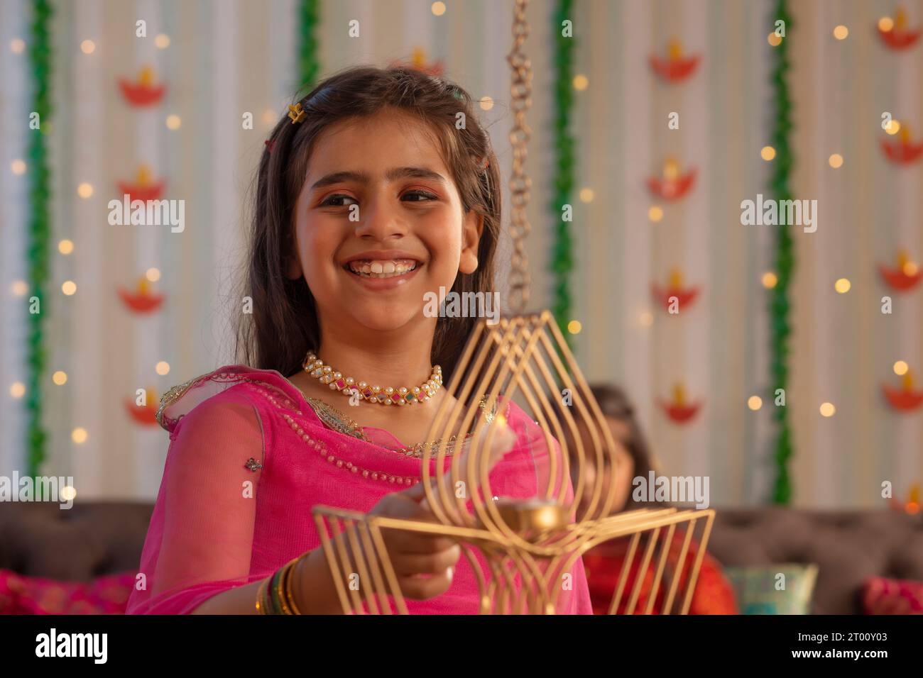 Portrait d'une jeune fille joyeuse allumant diya à l'occasion de Diwali Banque D'Images