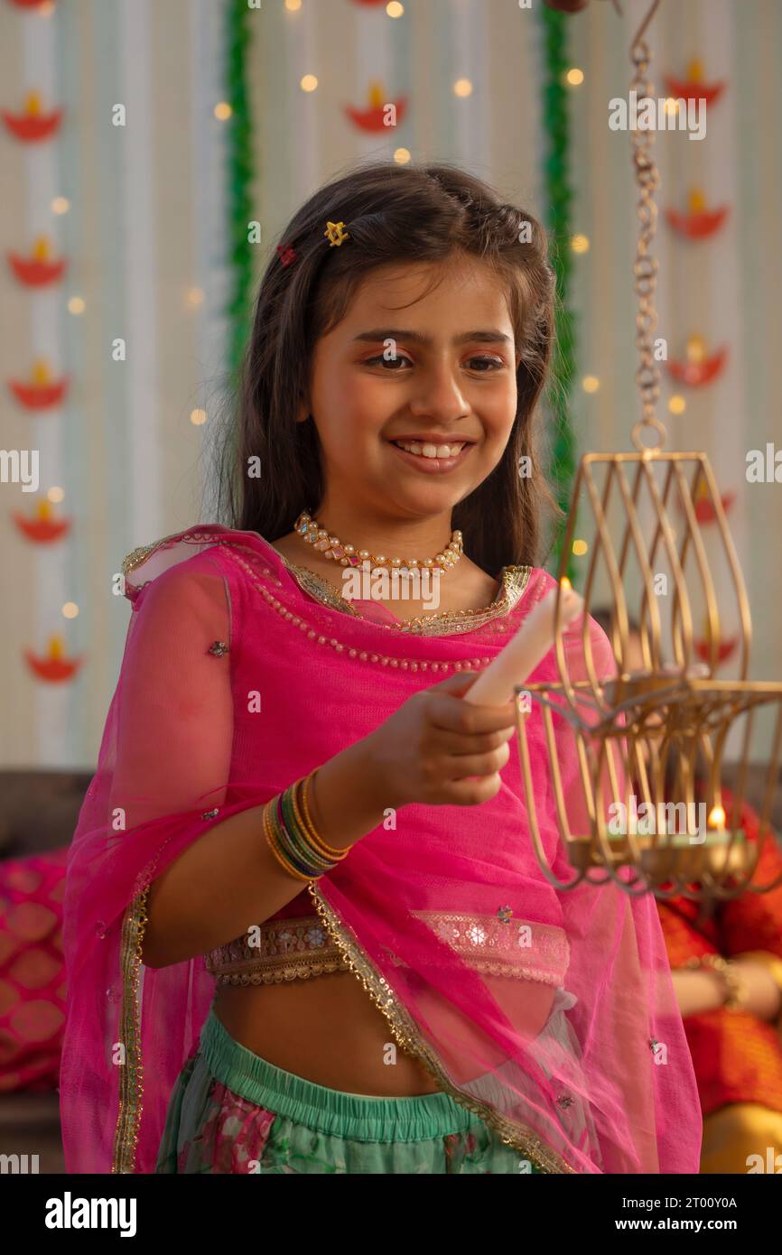Portrait d'une jeune fille joyeuse allumant diya à l'occasion de Diwali Banque D'Images