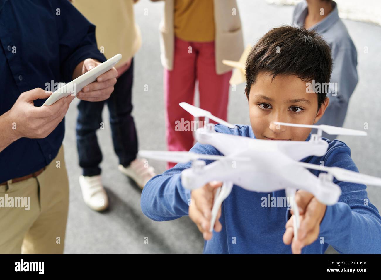Écolier aidant l'enseignant à lancer quadcopter via une tablette Banque D'Images