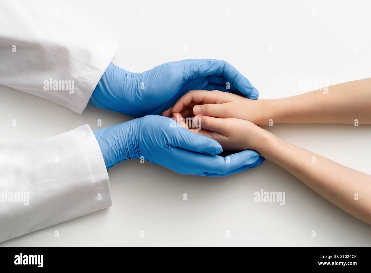 Les mains gantées du médecin tiennent les mains de l'enfant. Vue de dessus. Concept médical. Banque D'Images