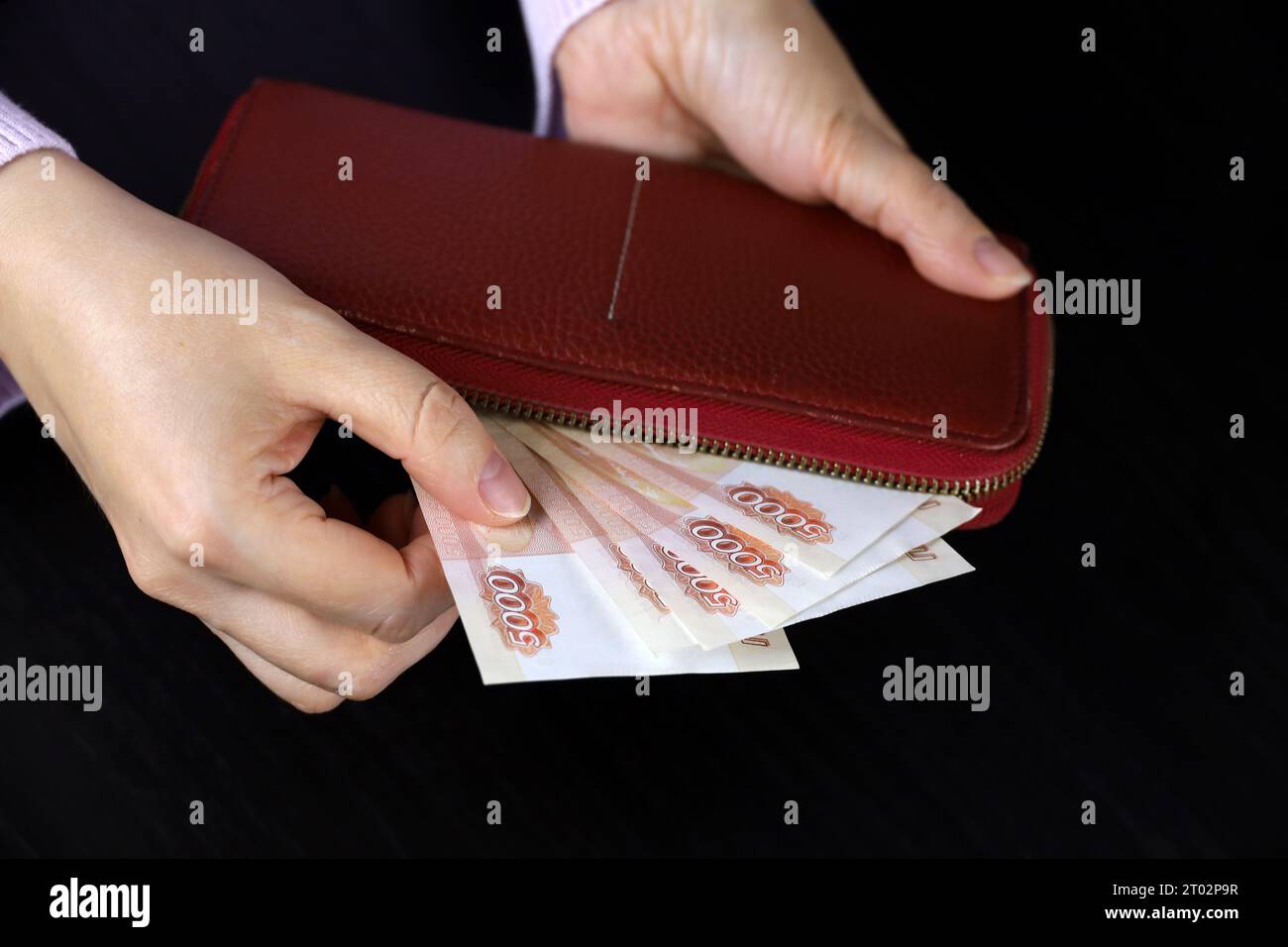 La femme sort des roubles russes du portefeuille rouge. Concept de salaires en Russie, paiements, assistance Banque D'Images