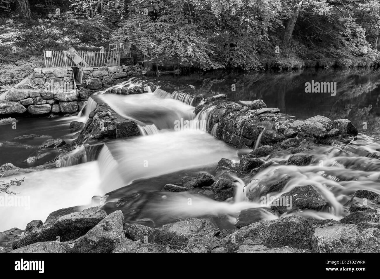 Longue exposition de la rivière Teign qui coule à travers le déversoir du château de Drogo dans le parc national de Dartmoor Banque D'Images