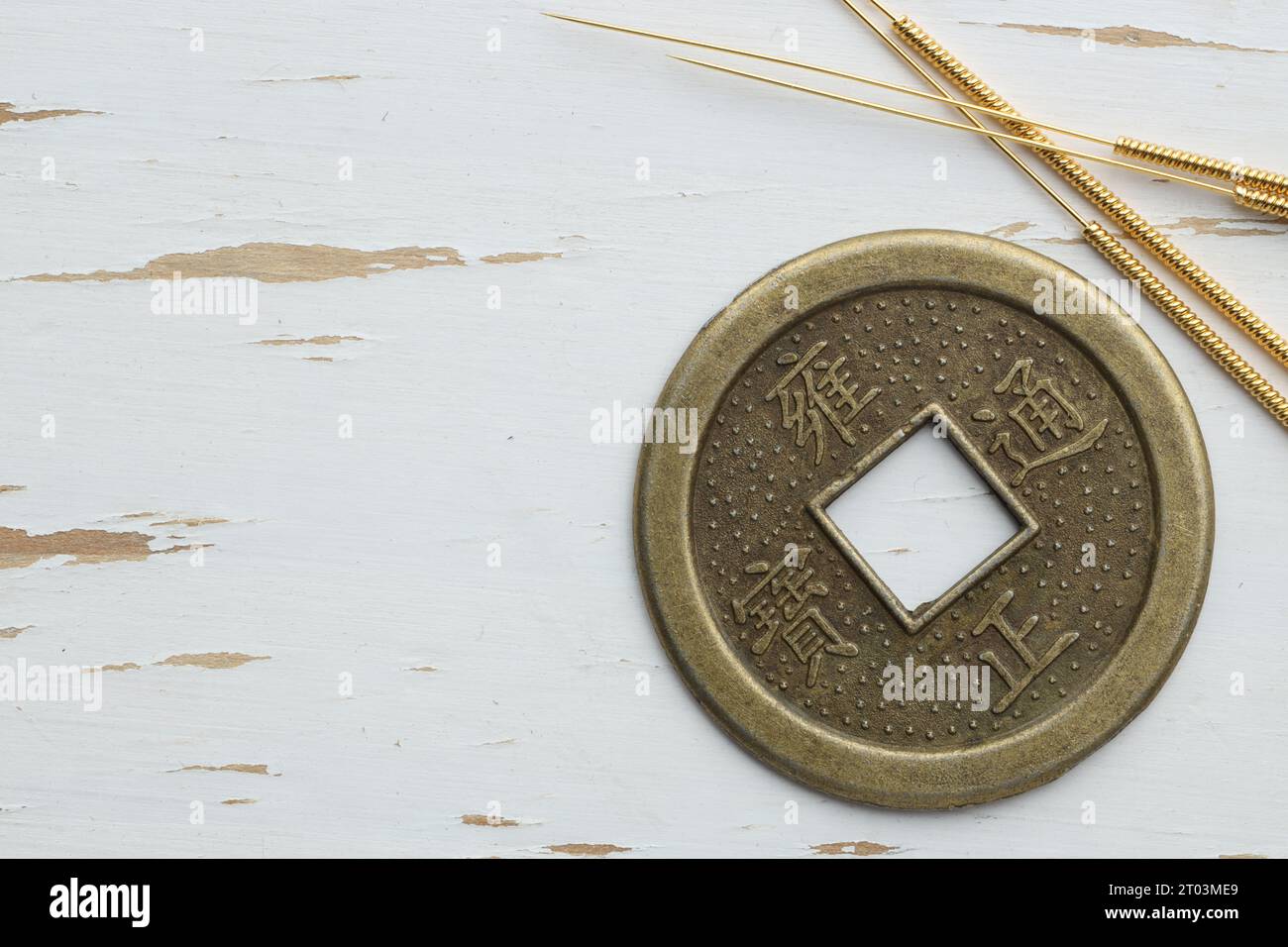 Aiguilles d'acupuncture et pièce de monnaie chinoise sur table en bois blanc, pose à plat. Espace pour le texte Banque D'Images