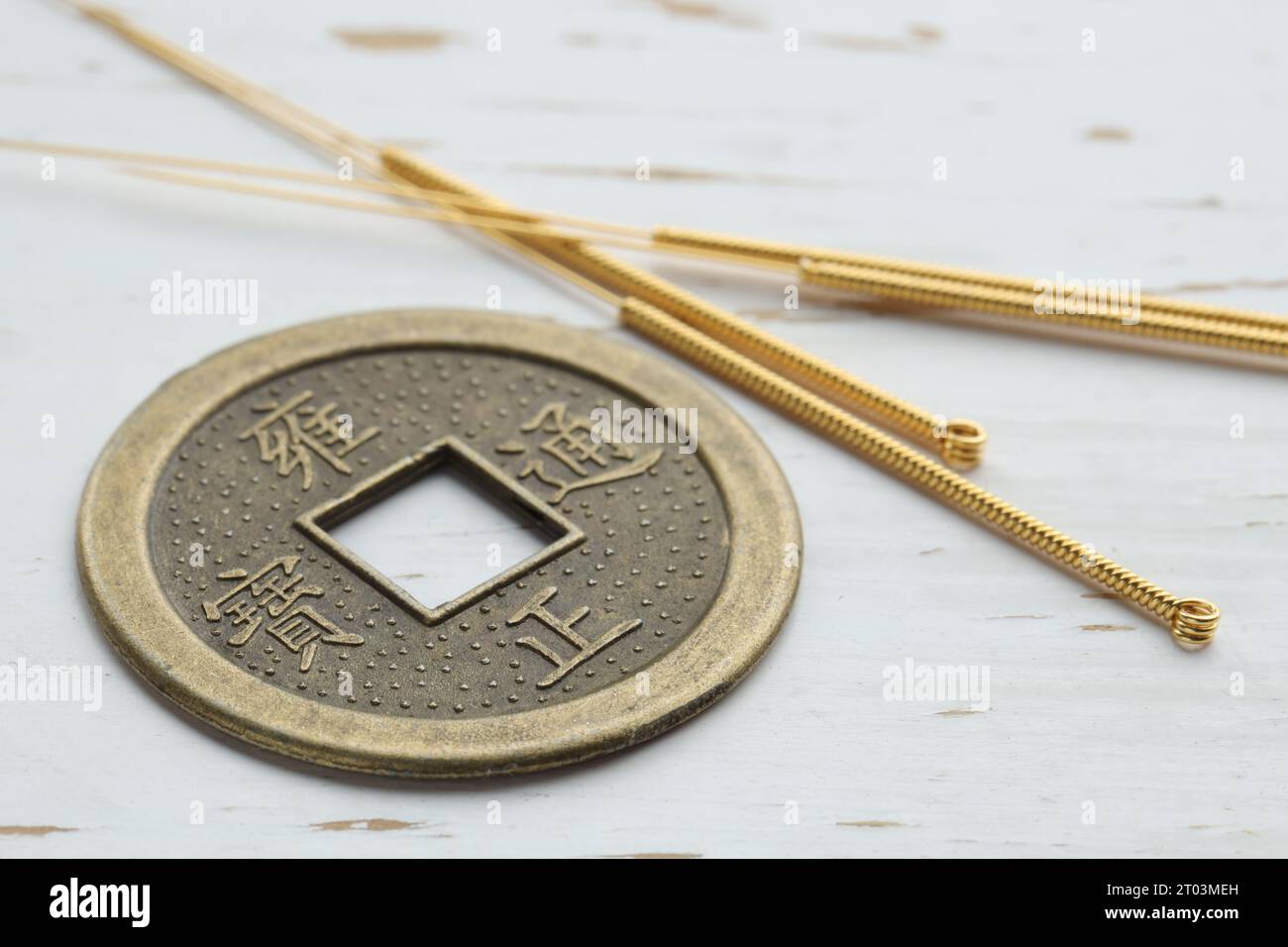 Aiguilles d'acupuncture et pièce chinoise sur table en bois blanc, gros plan Banque D'Images