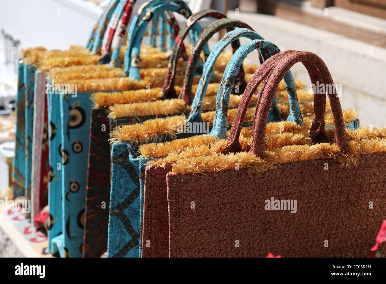 Une rangée de fourre-tout ou sacs à main excentriques, uniques, brodés soyeux, multicolores, avec poignées rigides arquées, Golden Tufts et divers motifs de conception. Banque D'Images