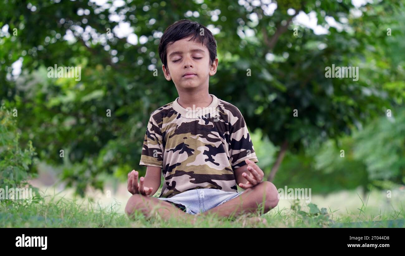 Mignon garçon assis pendant la méditation. Garçon de yoga. Enfant en position lotus. méditation relaxante ou assise pour enfant Banque D'Images