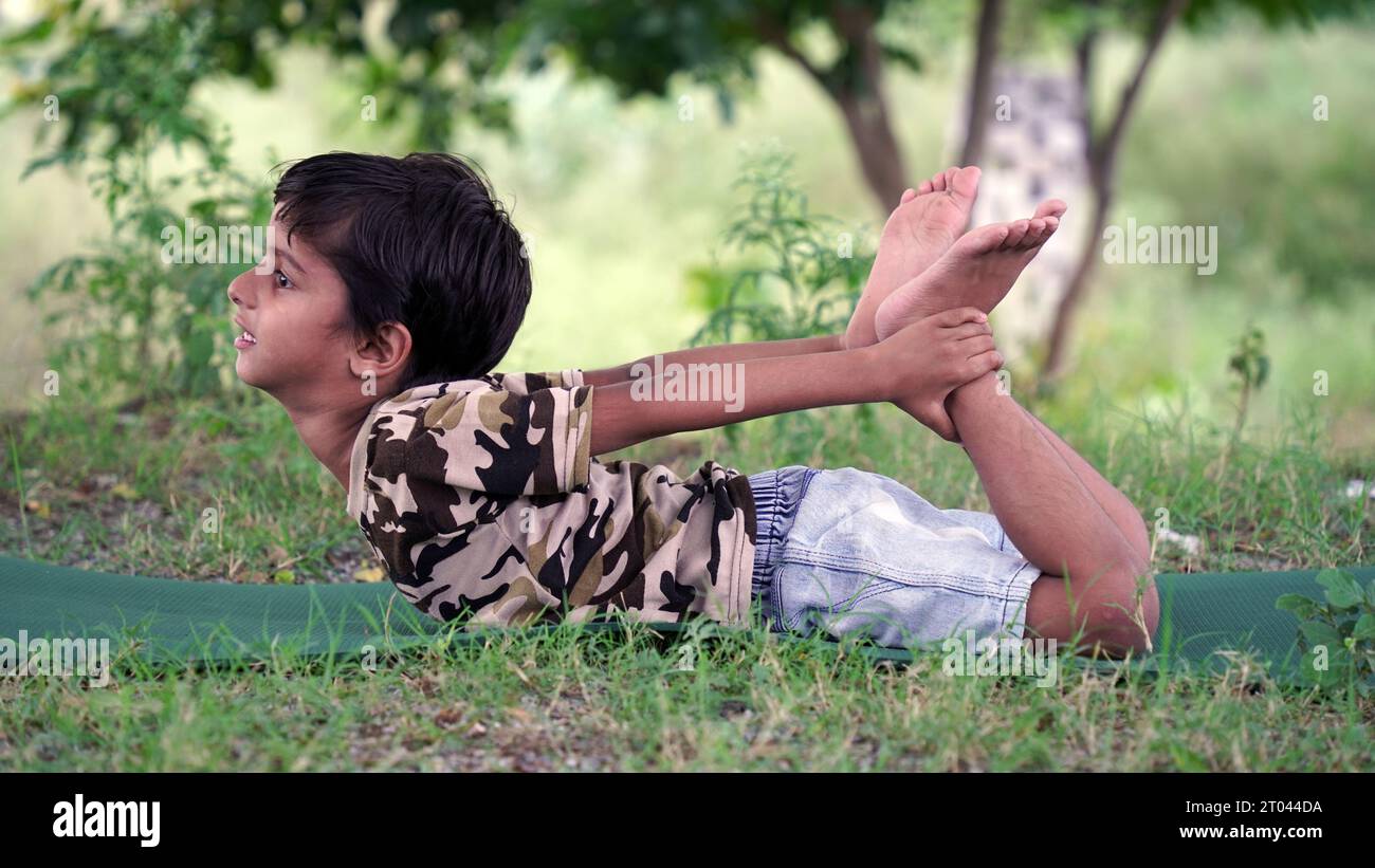 Portrait de magnifique enfant pratiquant le yoga en plein air. Bel enfant pratique le yoga asana ou fait des exercices de gymnastique. Petits enfants méditant dans lotus po Banque D'Images