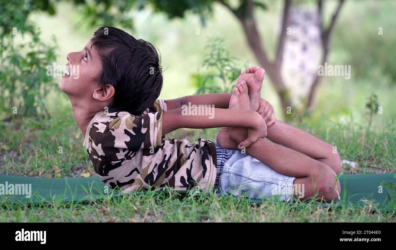 Portrait de magnifique enfant pratiquant le yoga en plein air. Bel enfant pratique le yoga asana ou fait des exercices de gymnastique. Petits enfants méditant dans lotus po Banque D'Images