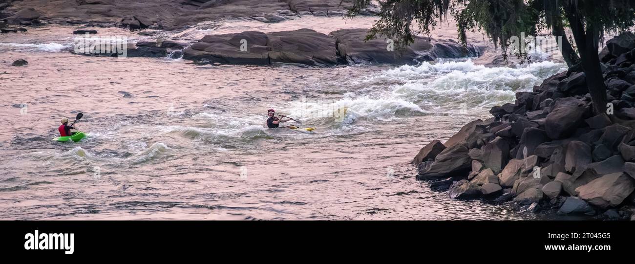 Kayakistes en eau vive freestyle au RushSouth Whitewater Park au crépuscule sur la rivière Chattahoochee entre Columbus, Géorgie, et Phenix City, ALABAMA. (ÉTATS-UNIS) Banque D'Images