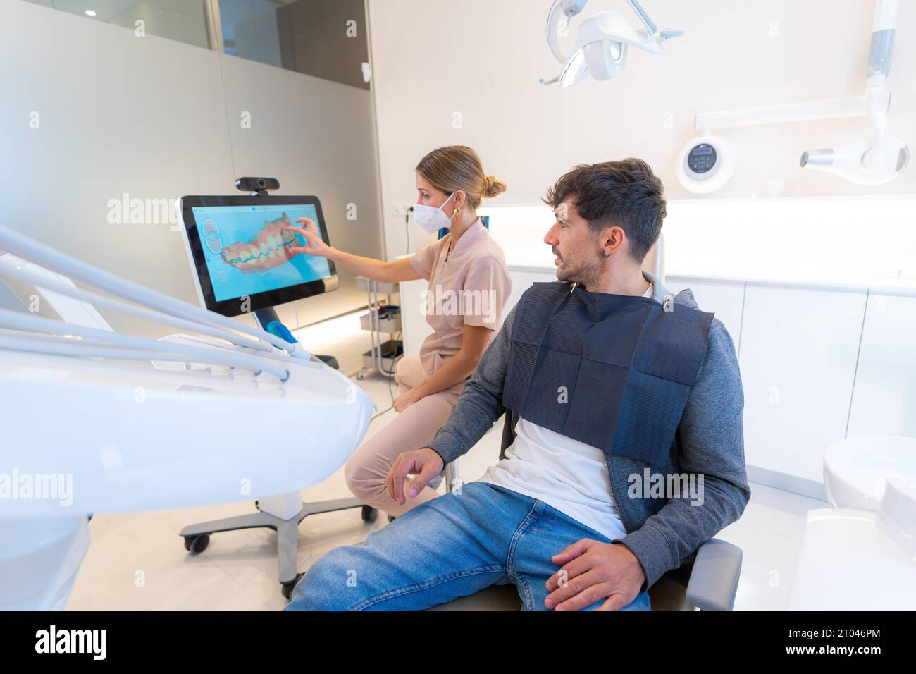 Dentiste utilisant la technologie moderne pour expliquer la procédure dentaire à un homme assis sur la clinique Banque D'Images