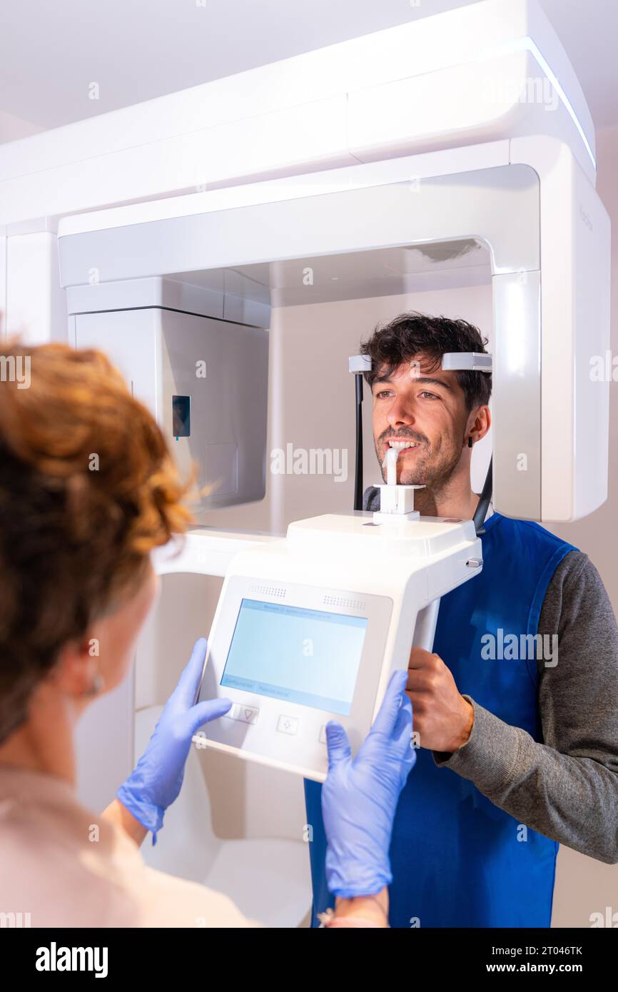 Photo verticale de la vue arrière d'un technicien utilisant un appareil radiographique dentaire avec un patient Banque D'Images Photo verticale de la vue arrière d'un technicien utilisant un appareil radiographique dentaire avec un patient Banque D'Images