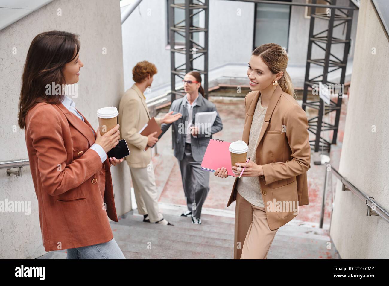 équipe en tenue intelligente avec paperasse et café bavarder sur les escaliers pendant la pause, coworking Banque D'Images