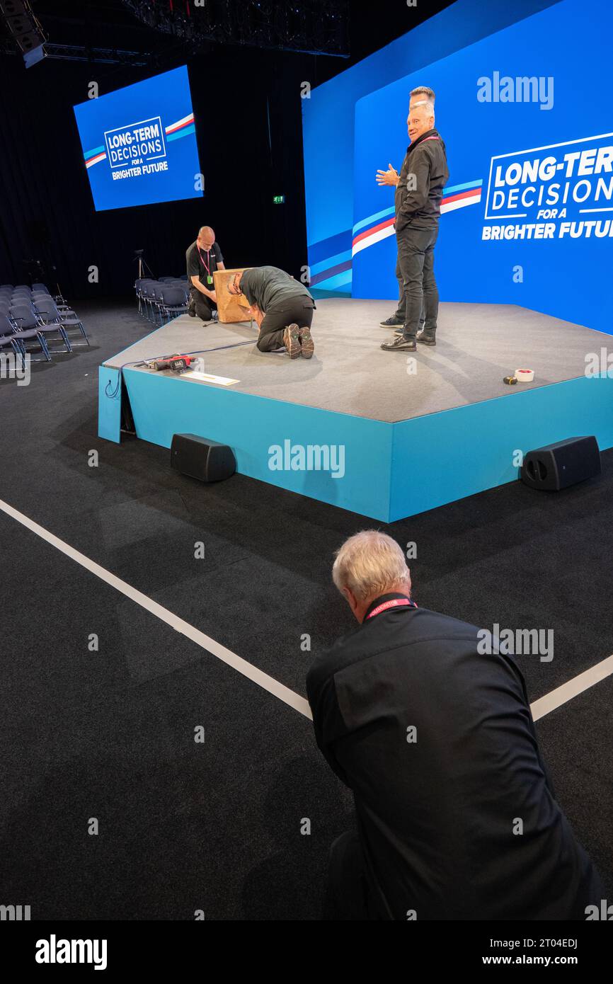 4 octobre 2023, Manchester, Royaume-Uni. Le podium est préparé et la bande magnétique est mise en place pendant que Grant Shapps fait les rondes d’interviews avec les médias alors que la salle principale est mise en place pour le discours des dirigeants avec Rishi Sunak. Manchester. ROYAUME-UNI. Crédit : GaryRobertsphotography/Alamy Live News Banque D'Images