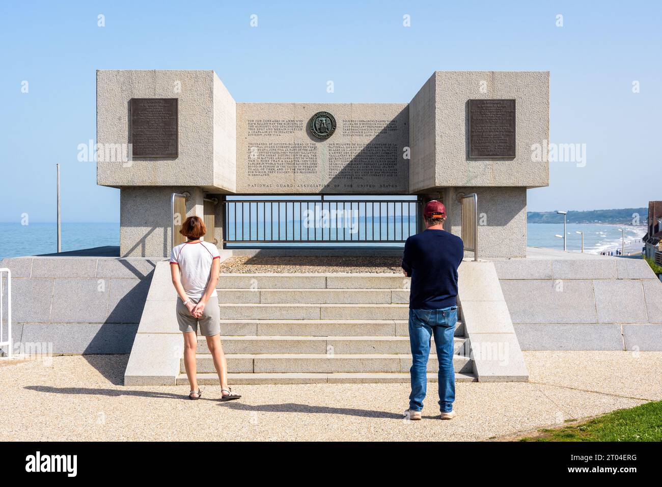 Touristes devant le Monument de la Garde nationale érigé en 2014 à Vierville-sur-Mer en mémoire des gardes nationaux qui débarquèrent sur Omaha Beach. Banque D'Images