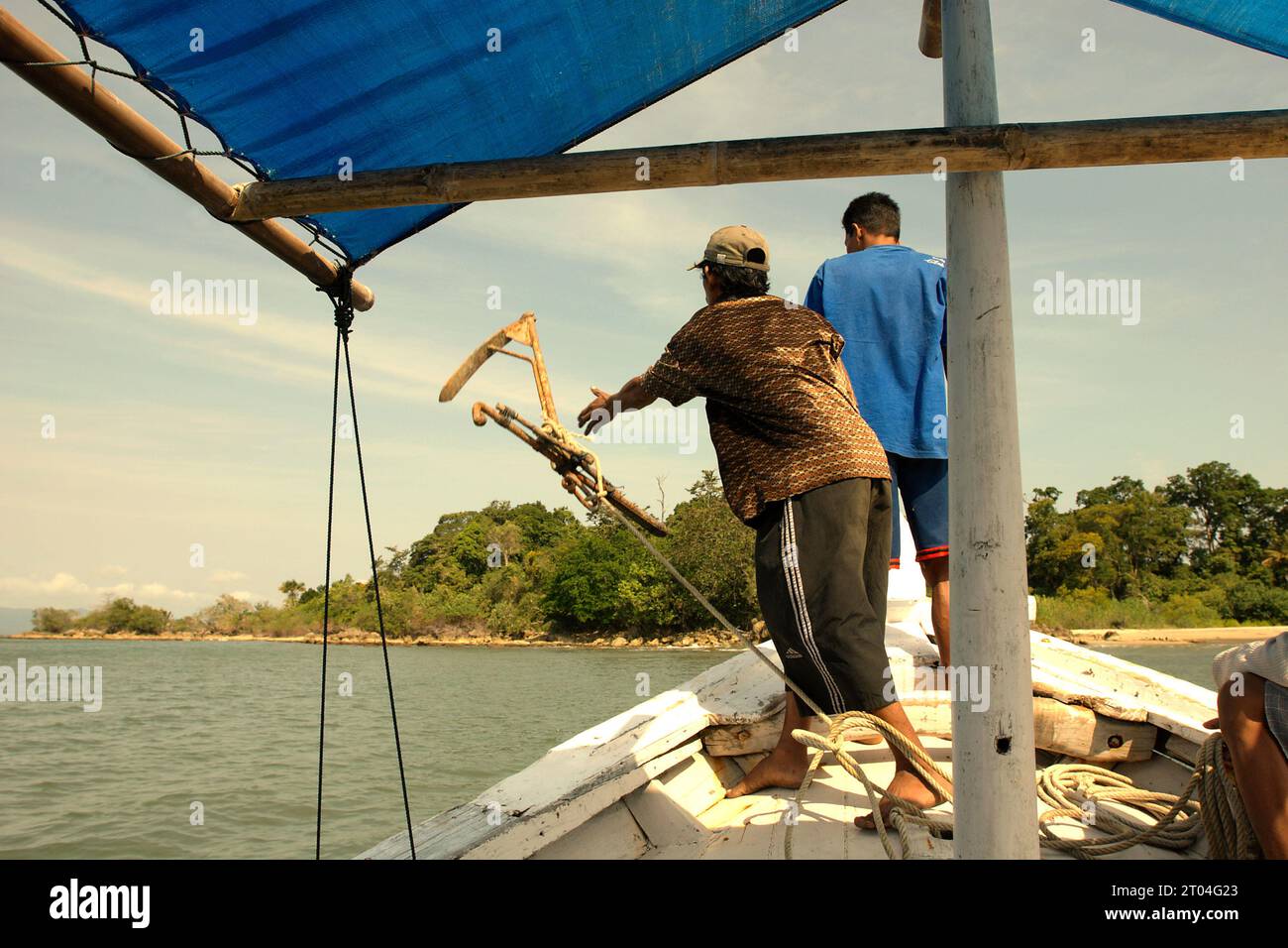 Un équipage jette une ancre alors qu’un bateau loué flotte sur les eaux côtières de l’île Handeuleum, une partie du parc national d’Ujung Kulon à Pandeglang, Banten, Indonésie. « Le parc national d'Ujung Kulon était une réserve faunique, qui a ensuite été étendue à la mer, principalement pour protéger l'écosystème des récifs coralliens dans la région ou comme zone tampon », ont écrit Tonny Soehartono et Ani Mardiastuti dans leur ouvrage de 2014 (gouvernance des parcs nationaux en Indonésie : leçons apprises de sept parcs nationaux). La plupart des parcs nationaux en Indonésie ont été créés dans les années 1980 et 1990 Les zones du parc étaient... Banque D'Images