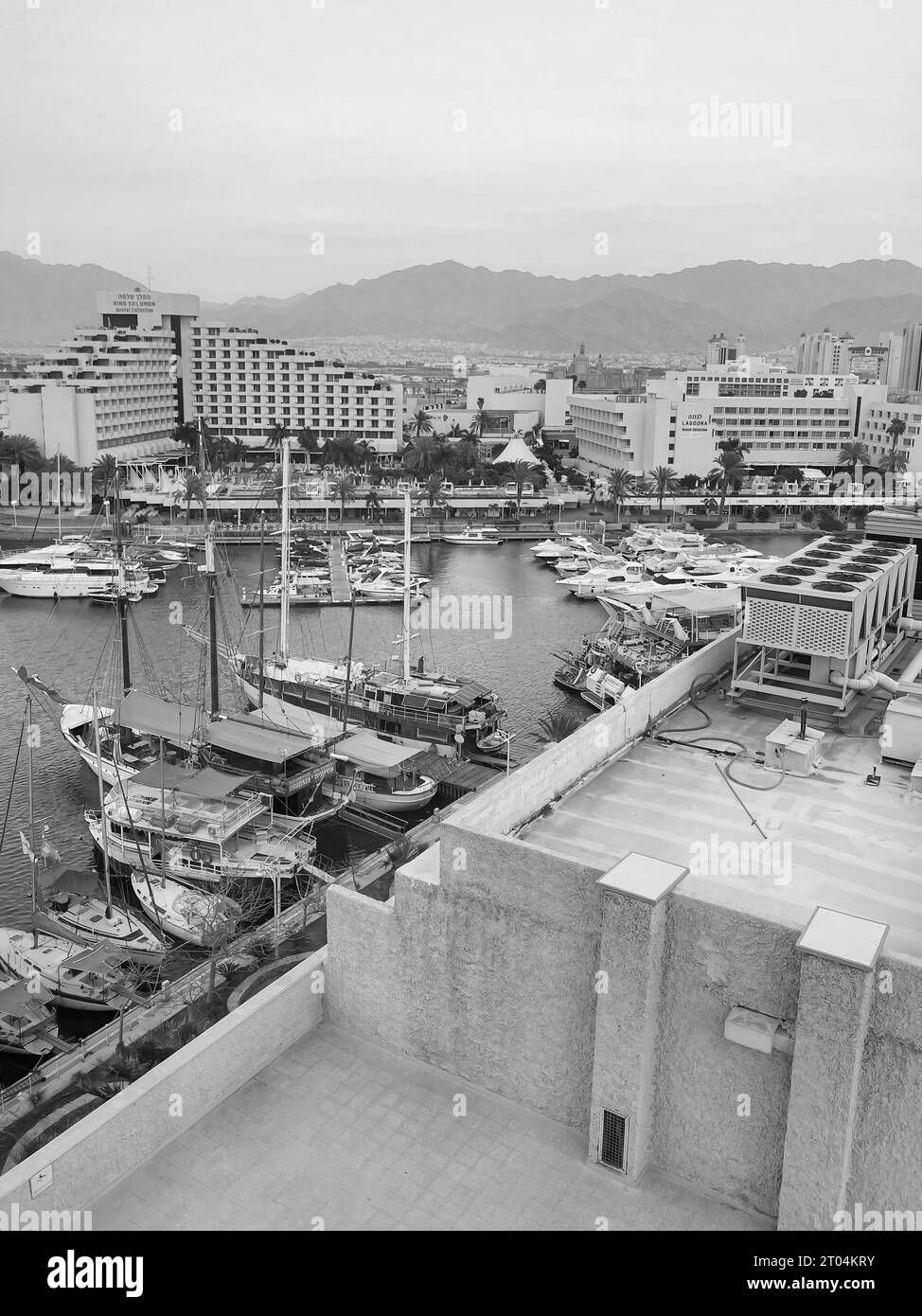 Port de plaisance d'Eilat en bord de mer avec des bateaux devant l'hôtel King Solomon et l'hôtel Lagoona tous deux près d'Isrotel en noir et blanc Banque D'Images