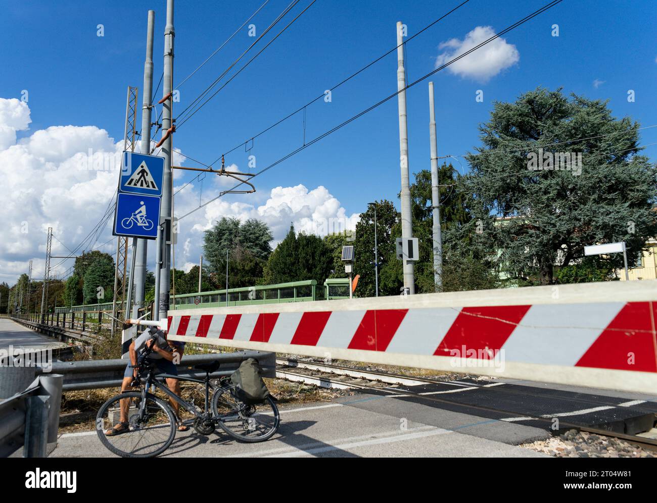 Un homme sur une bicyclette traverse les voies ferrées alors que la barre de passage bloque le passage à un passage à niveau télécommandé Banque D'Images