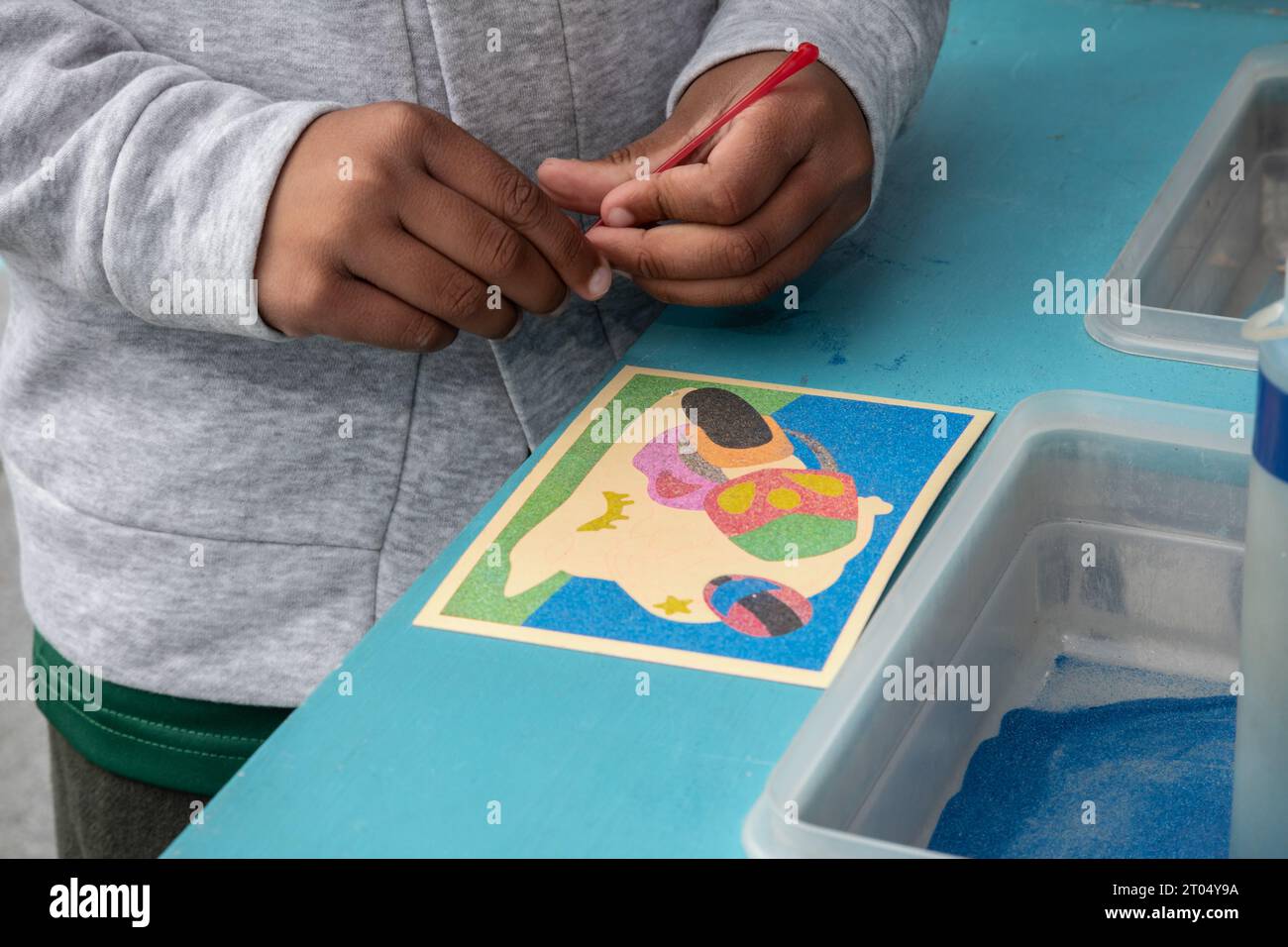 Une image rapprochée des mains d'un garçon s'immergeant dans l'activité de loisirs créative de l'art du sable Banque D'Images