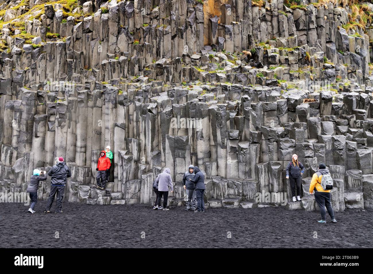 Touristes islandais sur la plage de sable noir de Vik, ou Reynisfjara plage, visite de la côte sud de l'Islande, falaises de basalte et résultats de l'activité volcanique ; Vik, Islande Banque D'Images