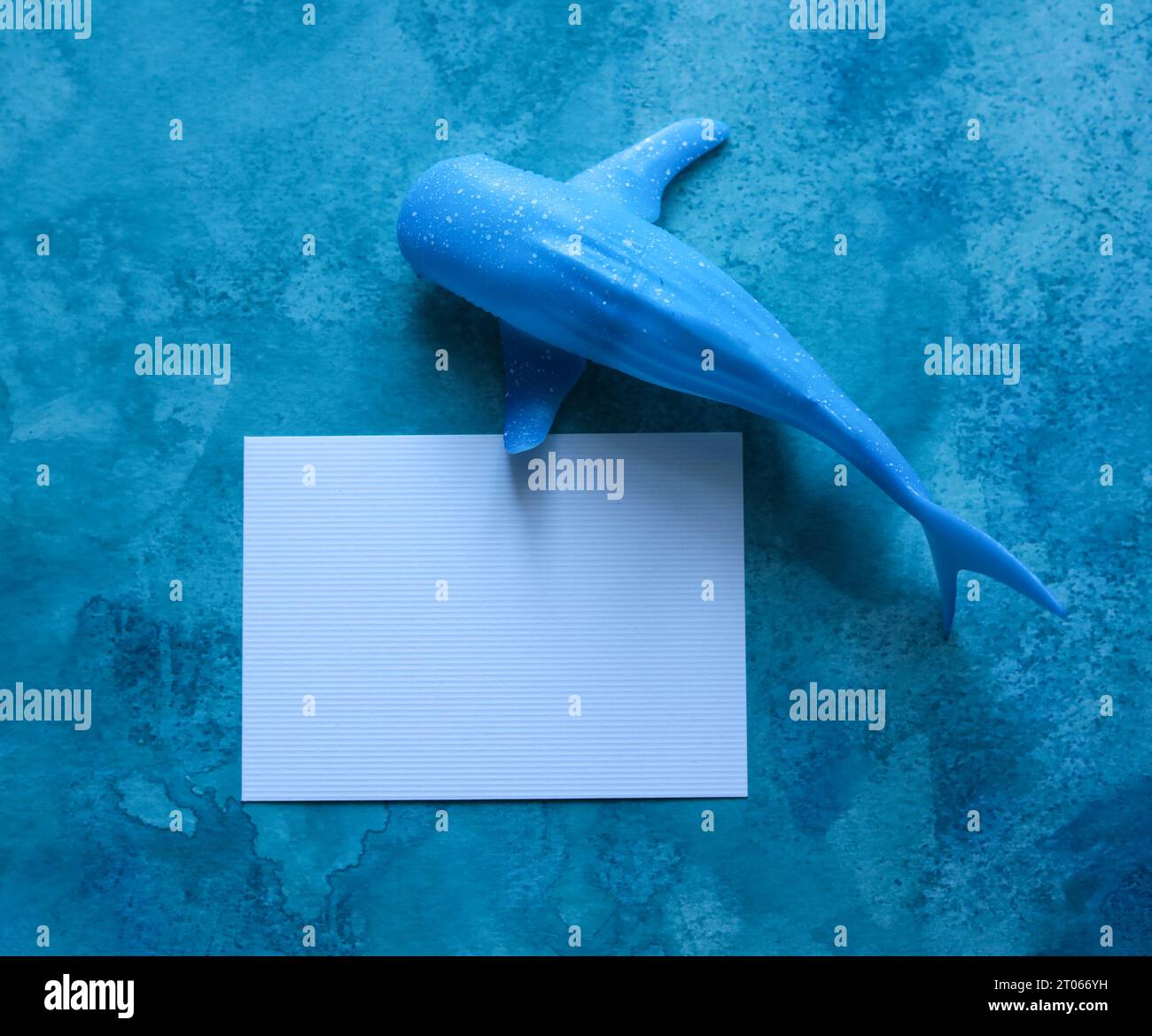 baleine jouet avec une carte de papier vierge avec un fond aquarelle bleu Banque D'Images