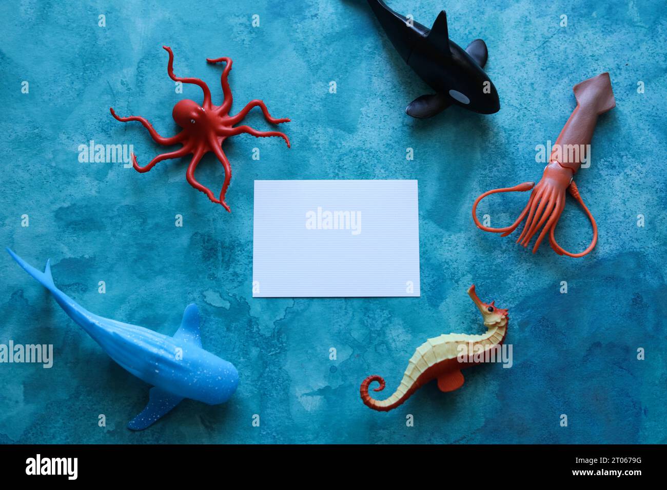 gros plan d'une carte vierge avec des jouets d'animaux de la vie marine sur un fond aquarelle bleu Banque D'Images