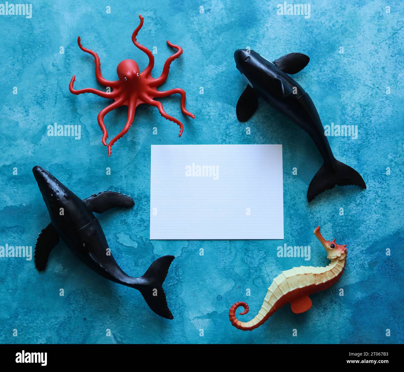 gros plan d'une carte vierge avec des jouets d'animaux de la vie marine sur un fond aquarelle bleu Banque D'Images