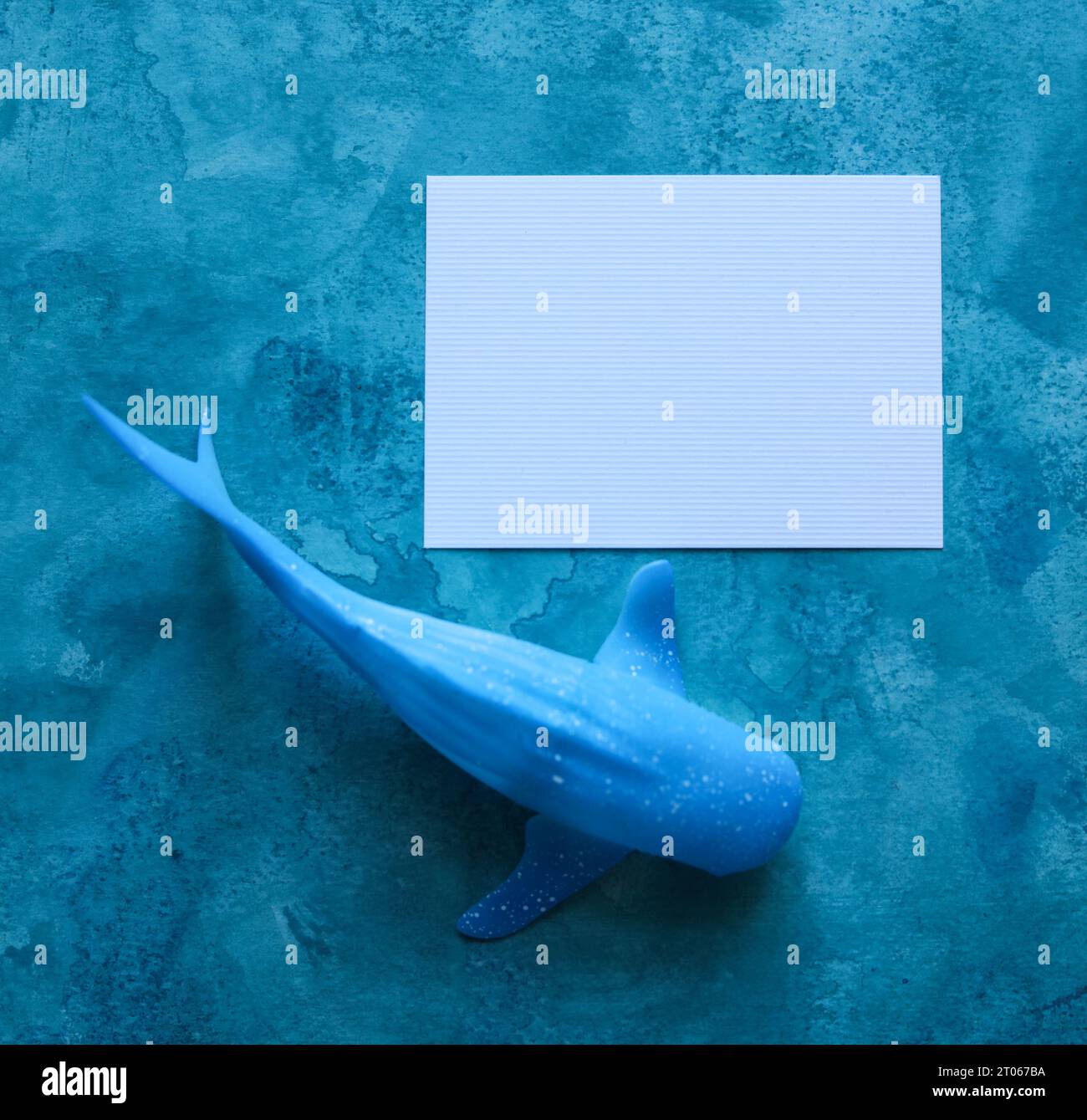baleine jouet avec une carte de papier vierge avec un fond aquarelle bleu Banque D'Images