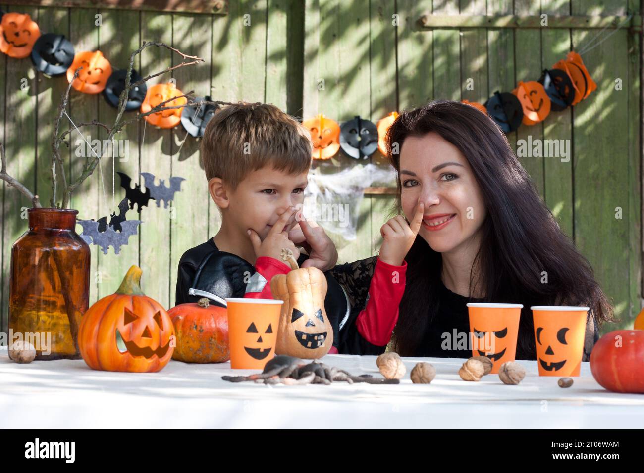 Portrait mère et fils le jour ensoleillé d'automne sur fond de vieux mur en bois. La mère et le fils de la famille se préparent pour Halloween, décorant la cour Banque D'Images