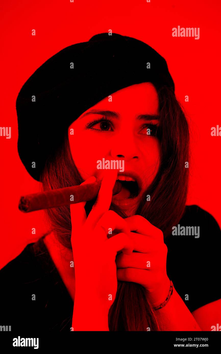 En noir foncé sur rouge, émerge un portrait d'une jeune femme, vêtue de béret, tenant un cigare, rappelant l'imagerie révolutionnaire emblématique. La ferveur du yo Banque D'Images